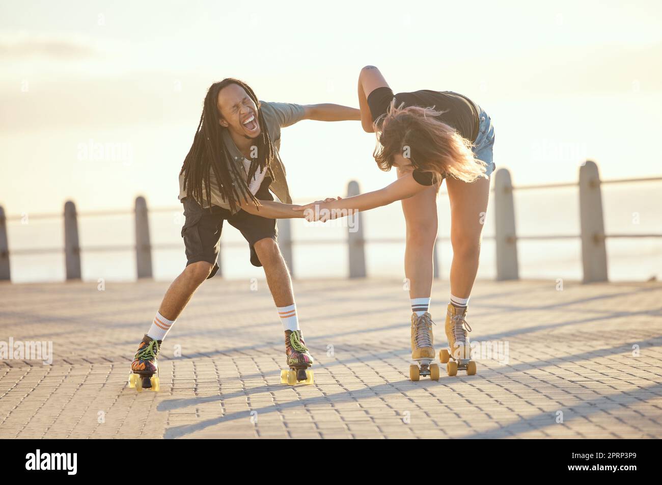 Libertà, divertimento e allegra coppia che ride e pattina all'aperto insieme, positivo, giocoso e allegro. Eccitato fidanzato interrazziale e fidanzata che sono pazzi mentre si divertono a pattinare Foto Stock