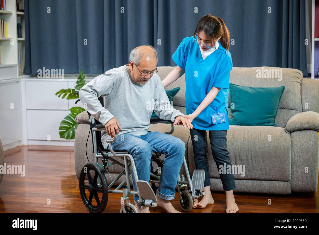 Infermiera asiatica che assiste il paziente anziano ad alzarsi dalla sedia a rotelle per esercitarsi a camminare Foto Stock