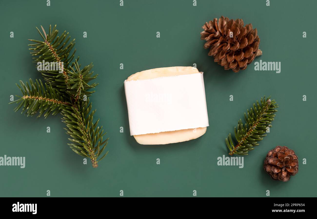 Sapone con etichetta vuota vicino ai rami di abete e ai coni di pino sulla vista dall'alto verde, mockup cosmetico Foto Stock