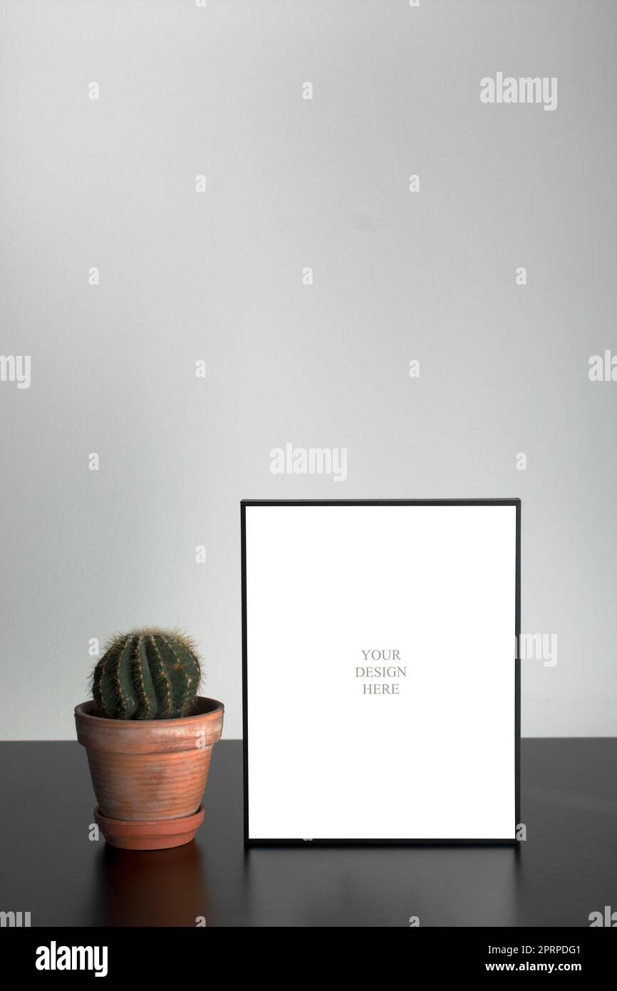 Mockup - cornice fotografica nera sul tavolo di legno nero con parete succulenta e bianca Foto Stock