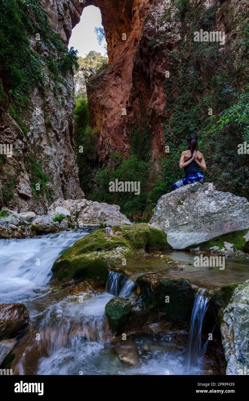 Donna che pratica yoga sul fiume, ponte di Dio, Akchour, Parco Naturale Talassettane, regione di Rif, marocco, africa Foto Stock