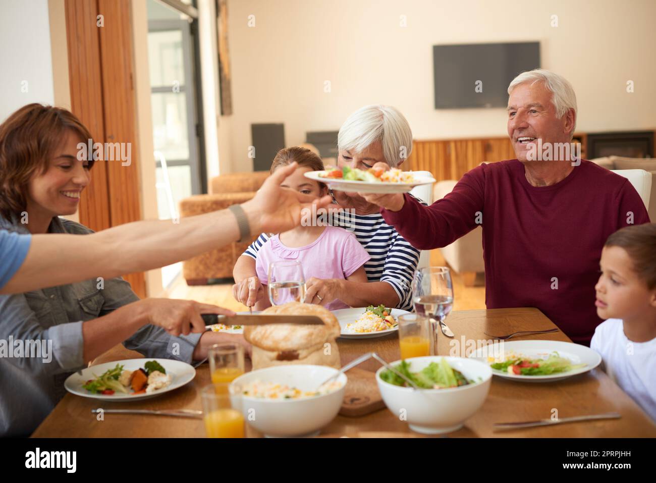 Il cibo è un'espressione di amore: Una famiglia multigenerazionale che mangia insieme attorno a un tavolo da pranzo. Foto Stock