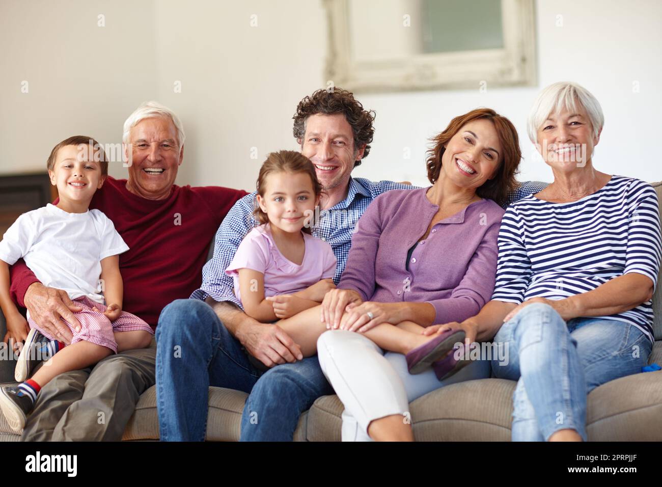 Amiamo i nostri incontri con la famiglia. Ritratto di una famiglia felice multi-generazionale seduto insieme su un divano. Foto Stock