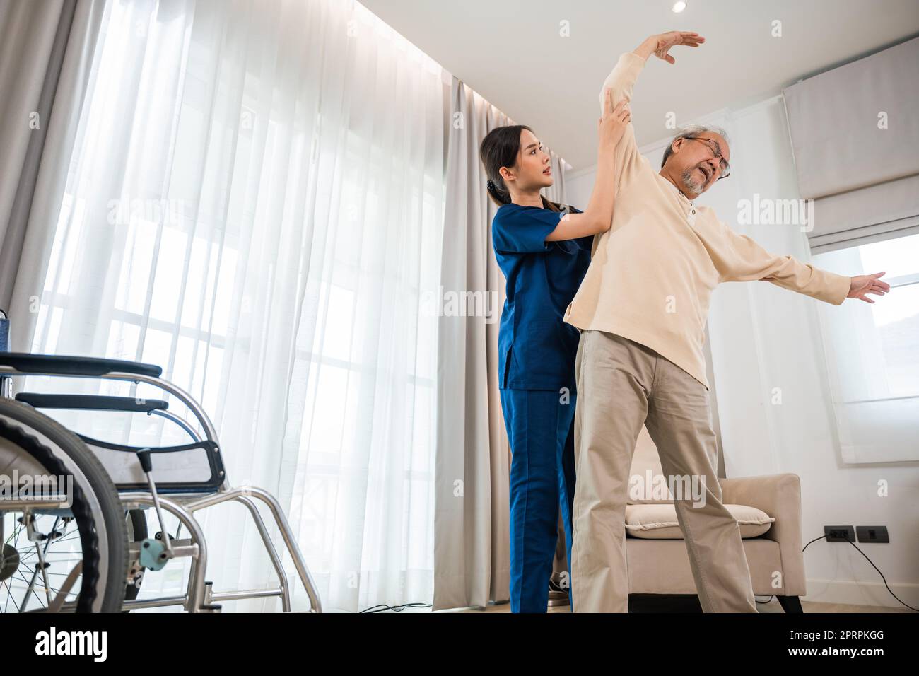 L'anziano ama allenarsi con il fisioterapista per le braccia distese a casa Foto Stock