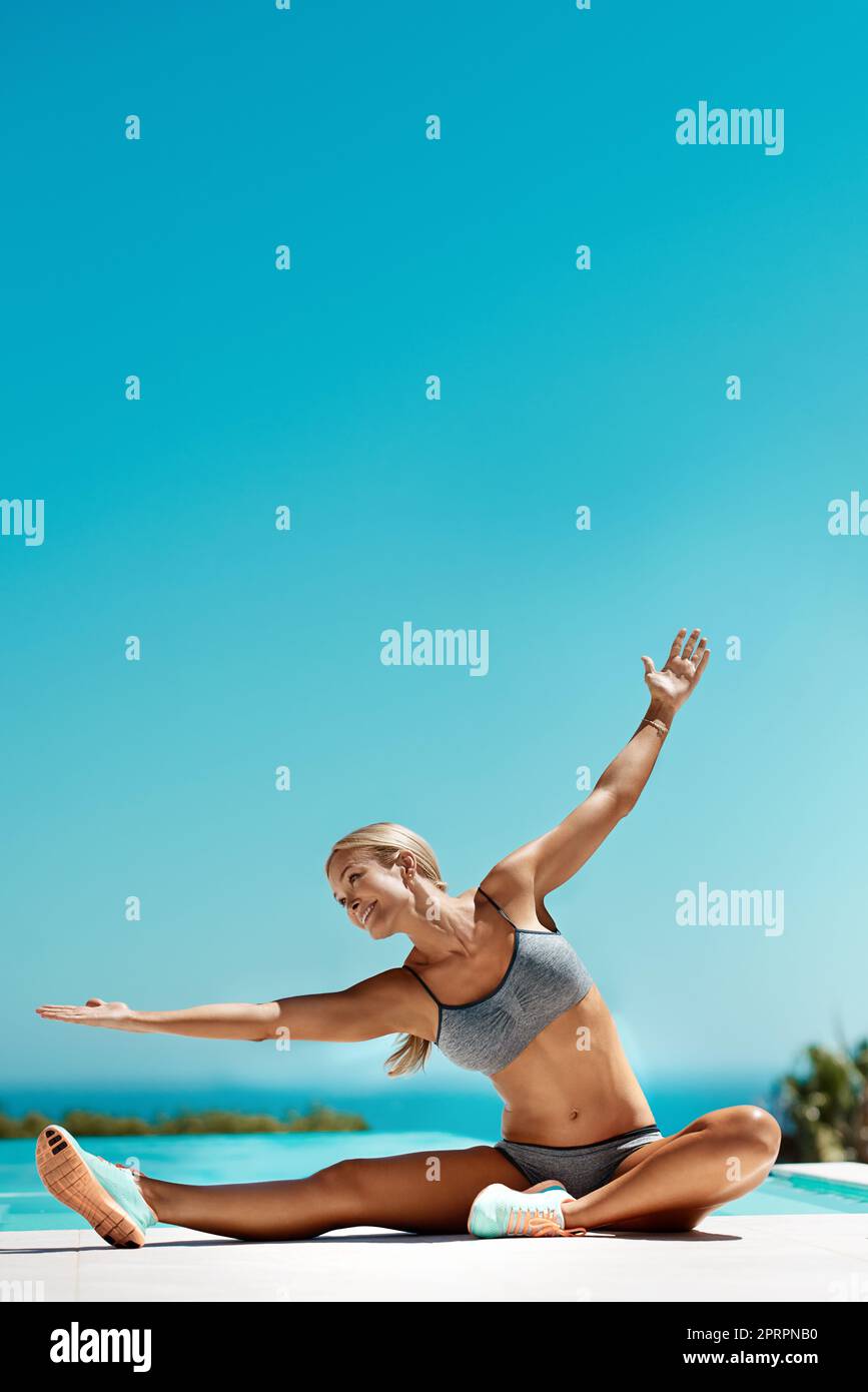 Tenere e respirare. Una giovane donna attraente che si allunga con le braccia distese dopo il suo allenamento in piscina in una giornata di sole. Foto Stock