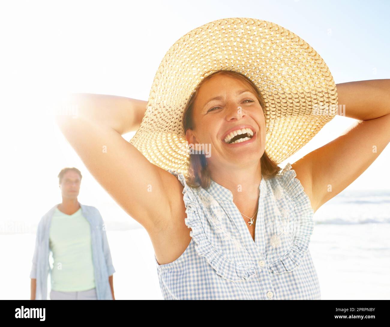 La libertà di essere se stessa. Una donna estatica che si gode una passeggiata sulla spiaggia con il marito. Foto Stock