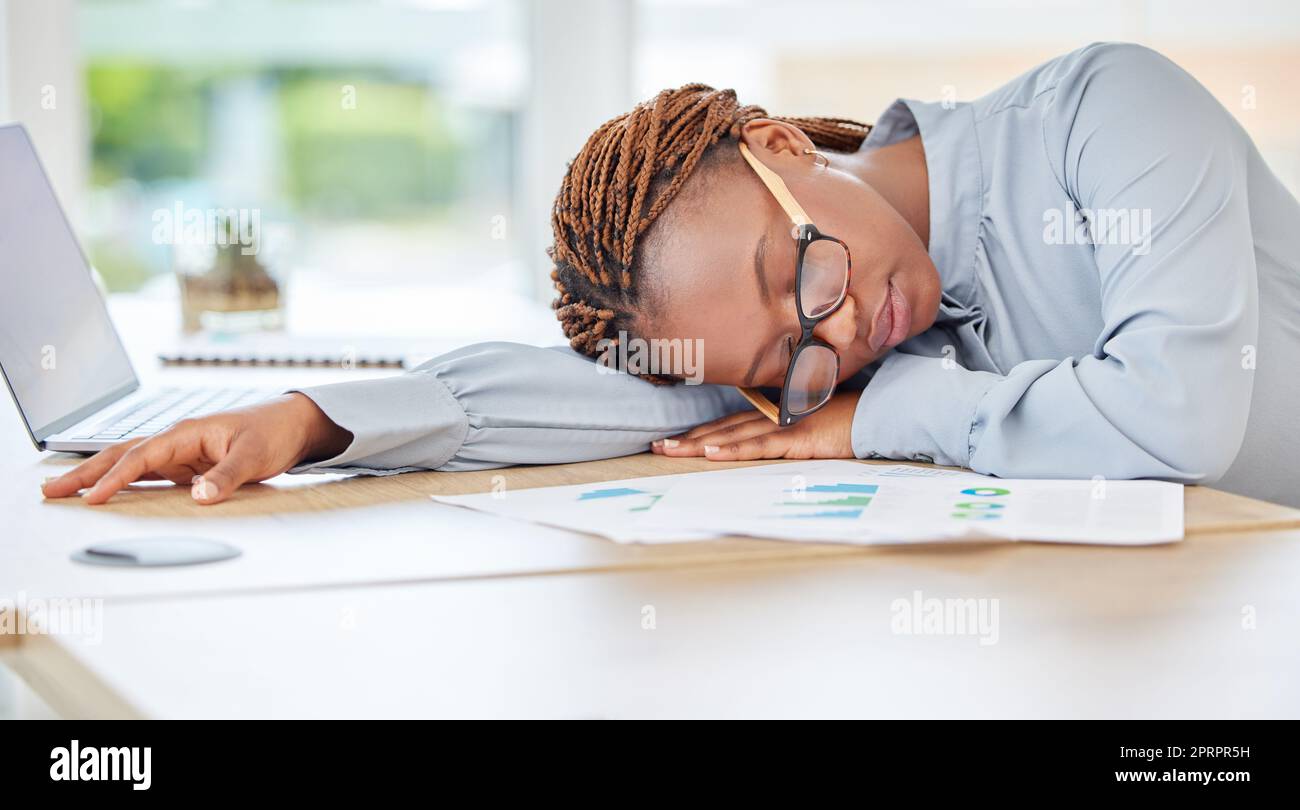 Donna nera che dorme, stanca o brucia in un ufficio finanziario con un notebook da scrivania o documenti infografici. Esausto, sovraccarico di lavoro o depressione per il dipendente addetto alla conformità contabile nel settore della revisione finanziaria Foto Stock