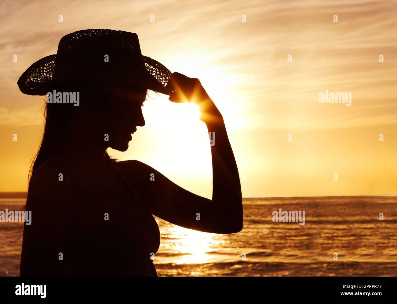 Donna che indossa un cappello di paglia contro il bel mare al tramonto. Adatta la donna indossando un cappello di paglia contro il mare bello al tramonto. Foto Stock