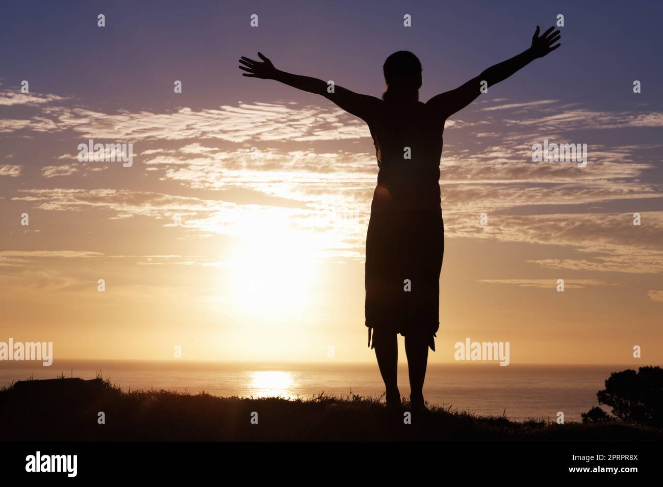 Godersi la vita. Silhouette di una donna in piedi al sorgere del sole con le braccia distese. Foto Stock