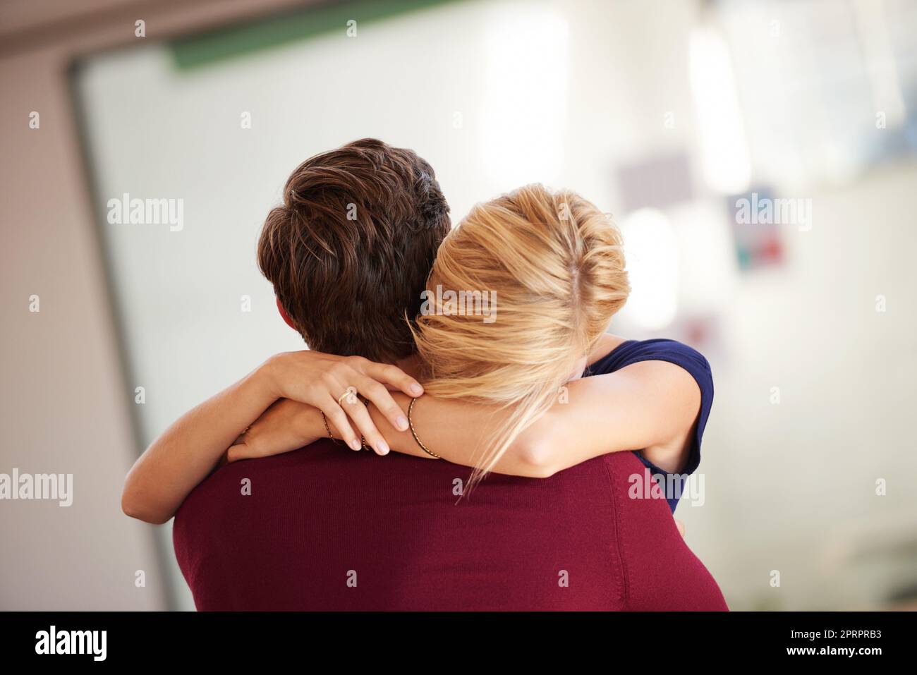 È iniziato come un romanticismo d'ufficio. Una coppia che abbraccia insieme in un ufficio aperto. Foto Stock