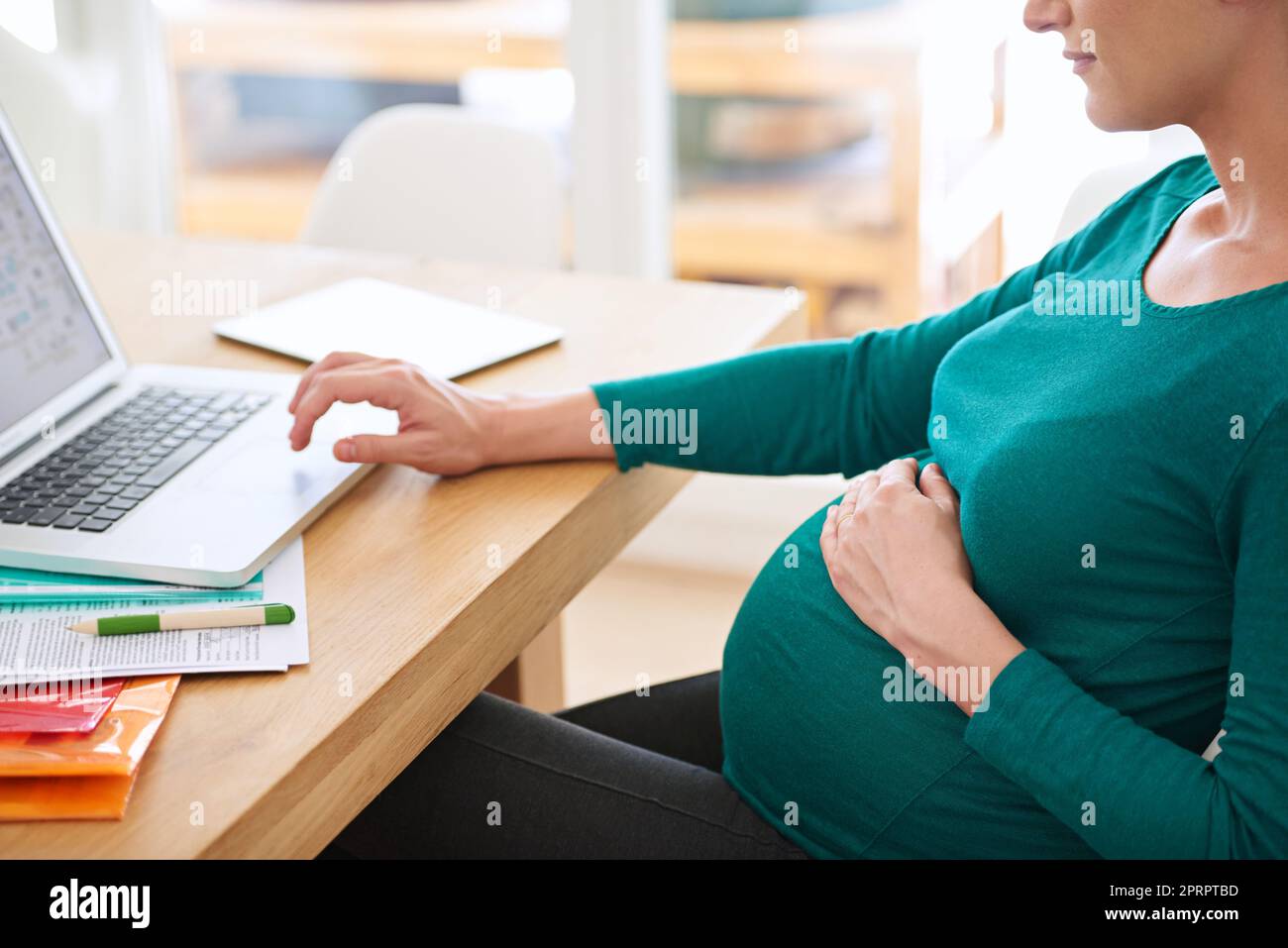 Raccogliere qualche consiglio genitorialità online. Una donna incinta che usa il suo notebook a casa. Foto Stock