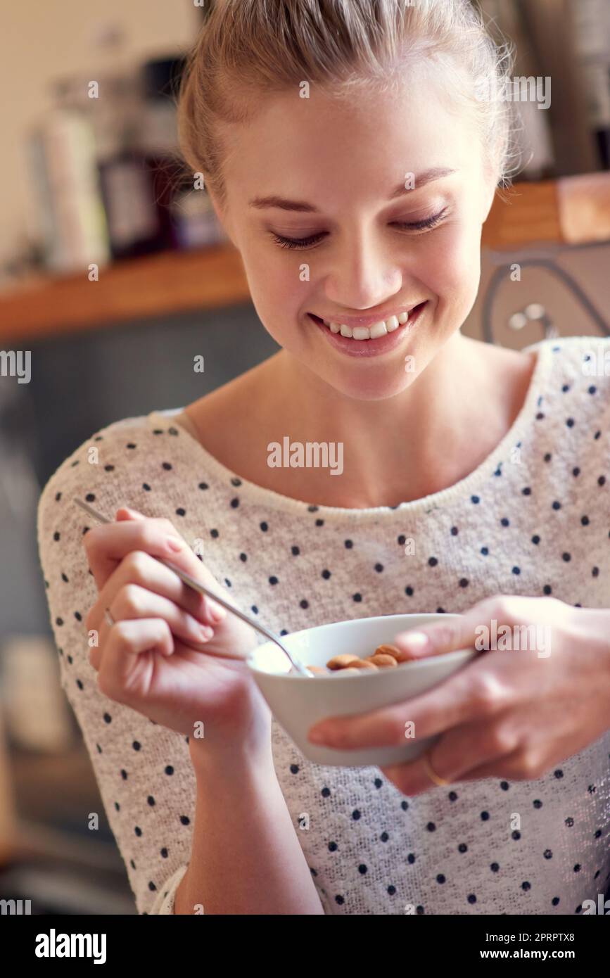 Spuntini sani - niente colpa, solo yum. Una giovane donna che mangia uno spuntino sano a casa. Foto Stock