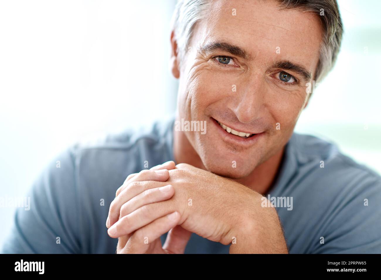 Imparare a rilassarsi. Ritratto di un bell'uomo maturo sorridente mentre guardava la fotocamera durante il giorno. Foto Stock