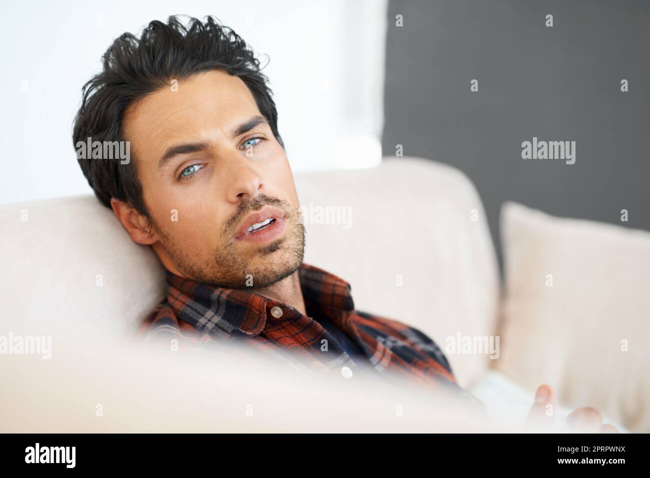 In una daze da sogno. Ritratto di un bel giovane sdraiato su un divano di casa. Foto Stock