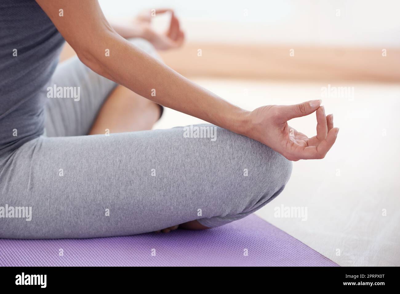 Serenità Zen-come. Un'immagine ritagliata di una donna seduta a gambe incrociate e meditante. Foto Stock