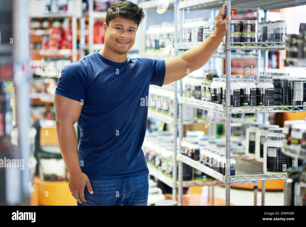 Il vostro negozio di supplemento di uno stope. Un giovane muscolare nella sezione supplemento di una farmacia. Foto Stock
