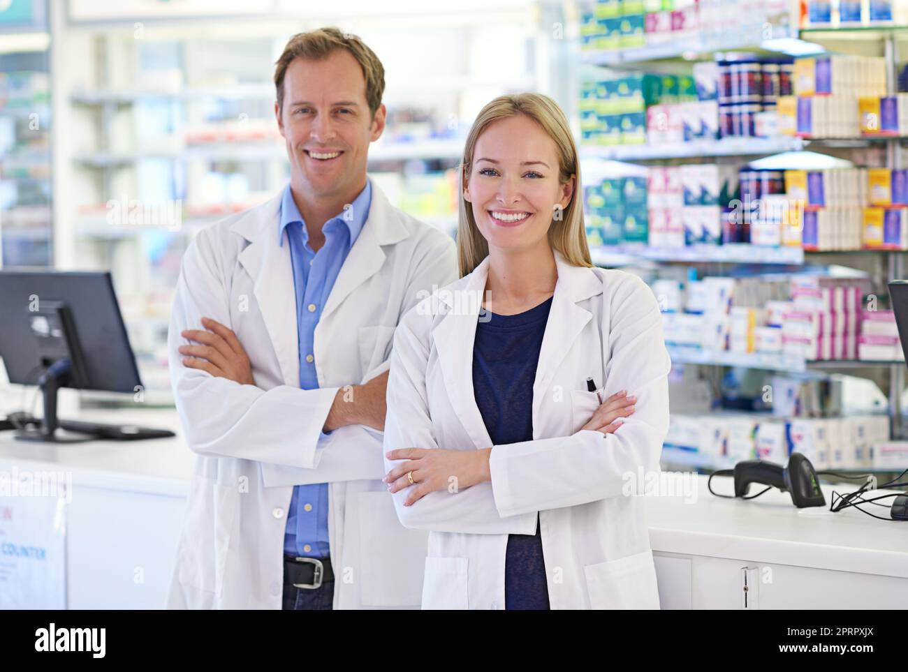 Farmacisti - qui per aiutare. Ritratto di due farmacisti in piedi al banco di prescrizione. Foto Stock