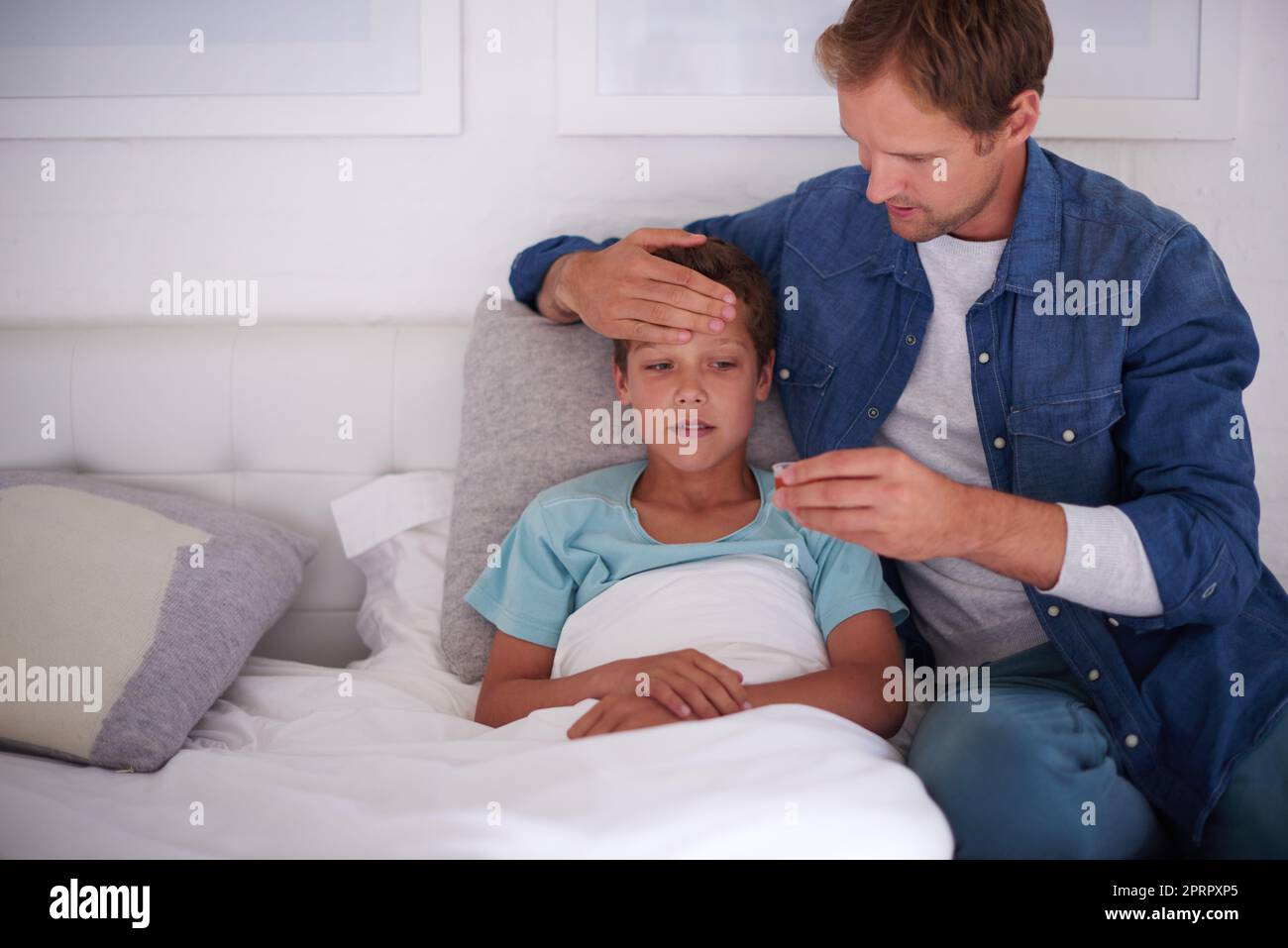 Papà sa bene: Un padre si prende cura del suo ragazzino ammalato a casa. Foto Stock