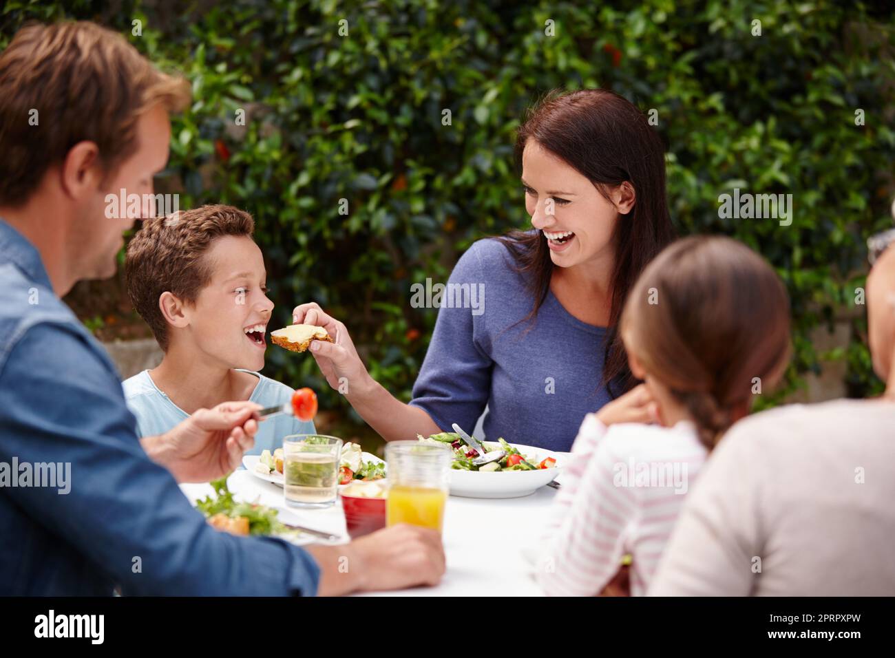 Condividere è prendersi cura, una famiglia felice multi-generazionale che ha un pasto insieme all'esterno. Foto Stock