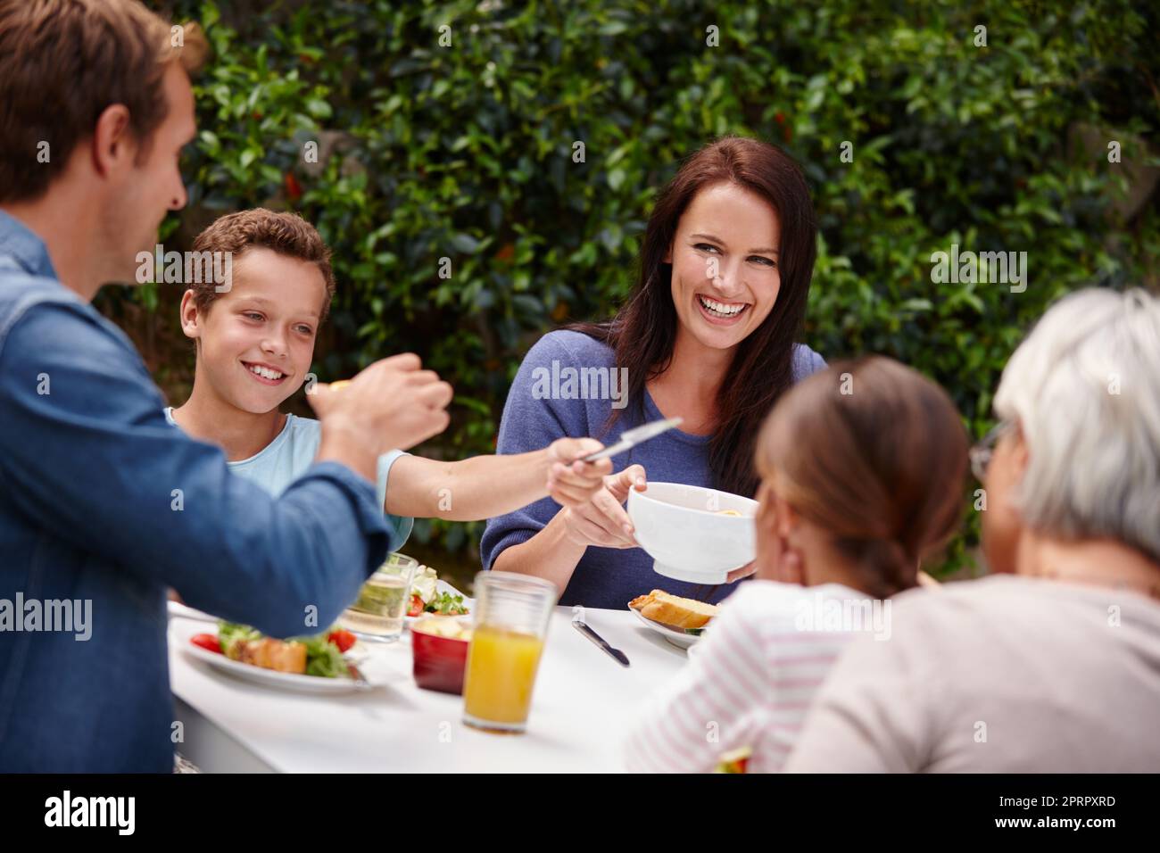 La famiglia è la benedizione più grande di tutta la vita, una famiglia felice multi-generazionale che ha un pasto insieme fuori. Foto Stock