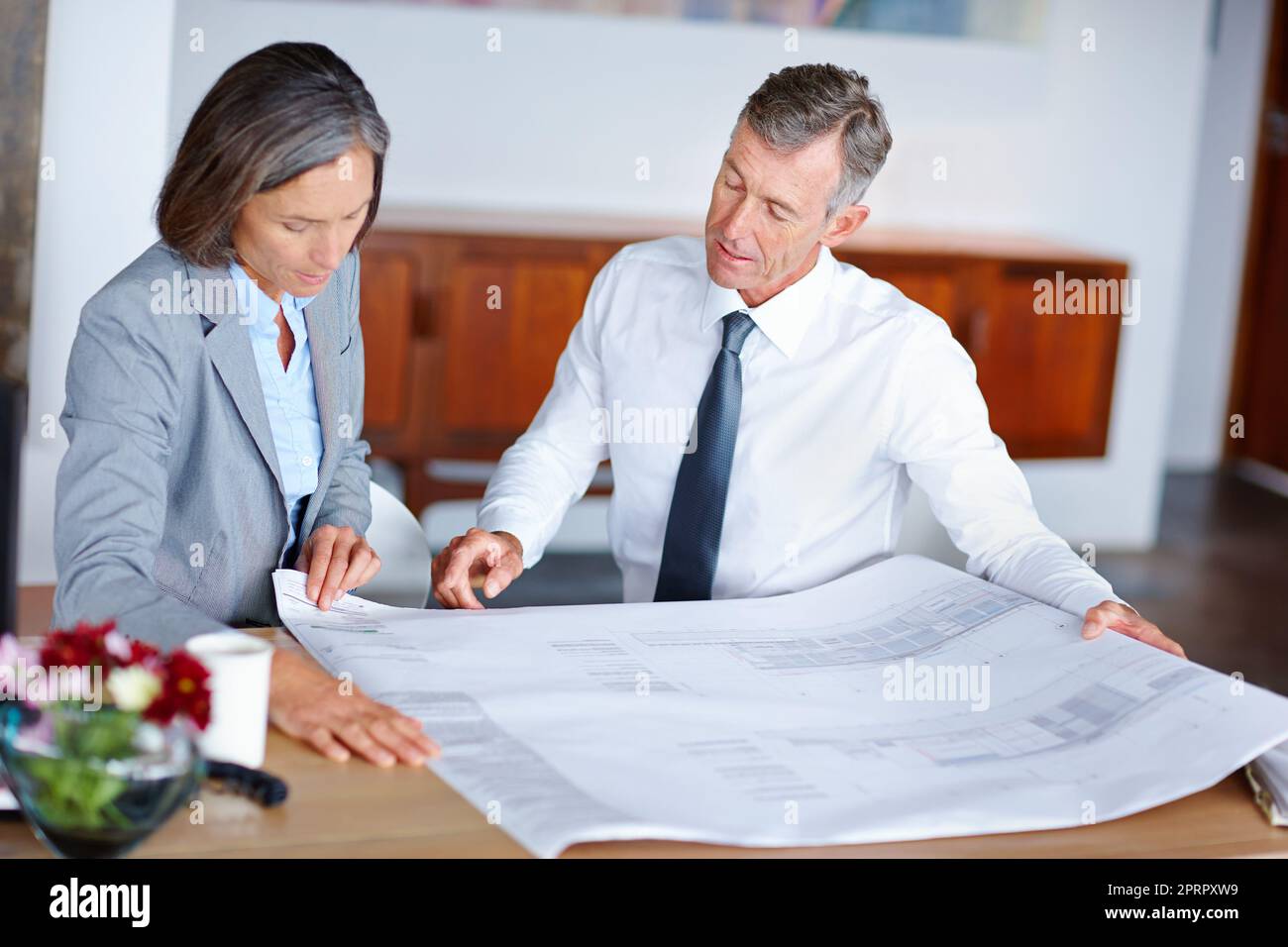 Valutare i piani. Due architetti maturi che discutono i progetti in un ufficio. Foto Stock