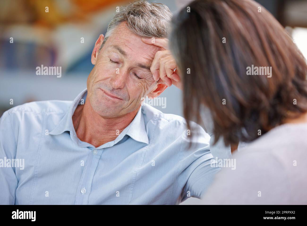 Qui andiamo di nuovo... un uomo maturo che guarda annoiato mentre i suoi wifes parlano con lui. Foto Stock