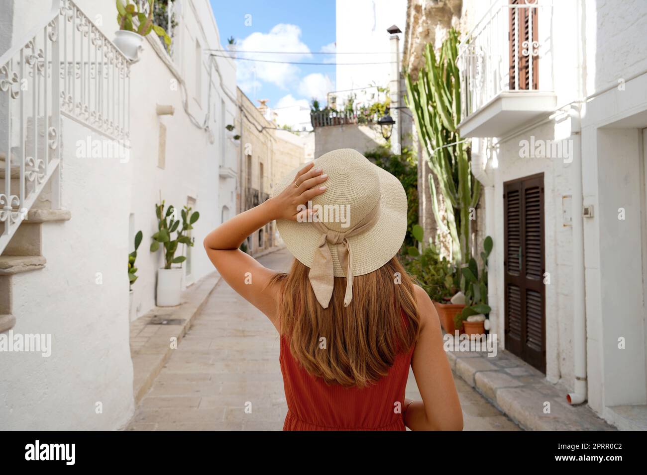 La ragazza viaggiante cammina attraverso i vicoli in una pittoresca cittadina della Puglia, Italia Foto Stock