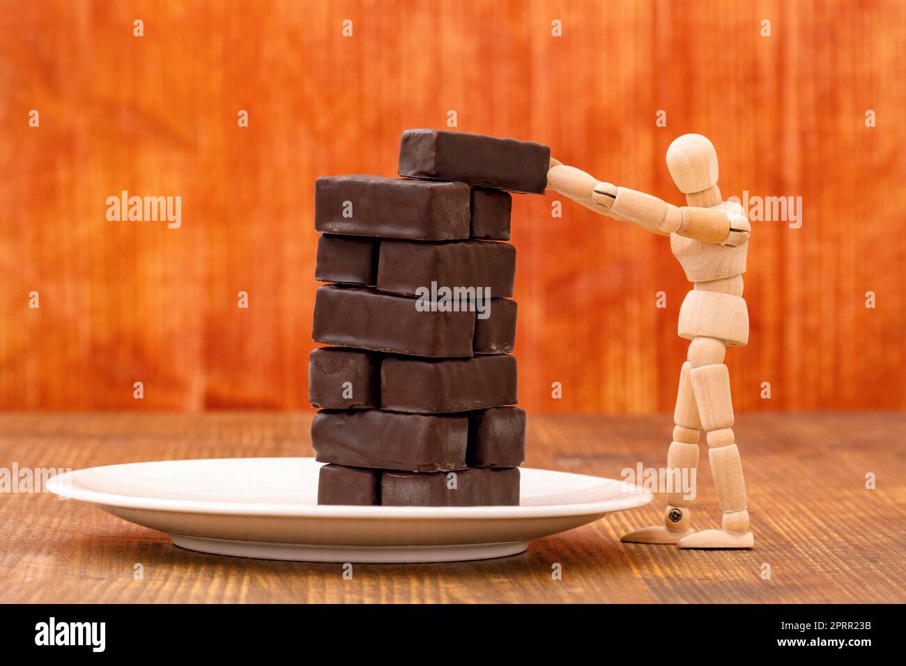 Manichino che prende una caramella al cioccolato da una torre di caramelle Foto Stock