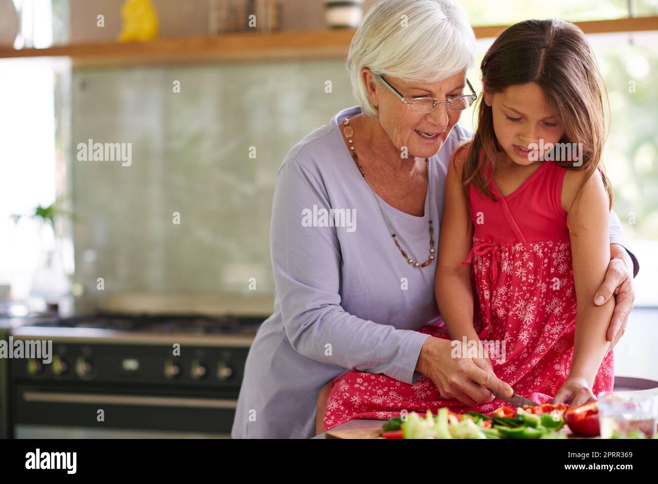 Un giorno sarai un grande cuoco. Una bambina che aiuta sua nonna a pranzare. Foto Stock