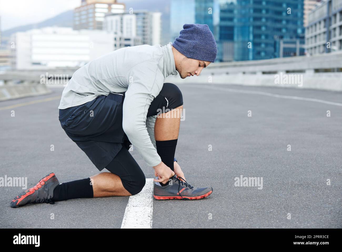 Preparazione dell'ultimo minuto prima della corsa. Un giovane che si allaccia prima di una corsa in città. Foto Stock