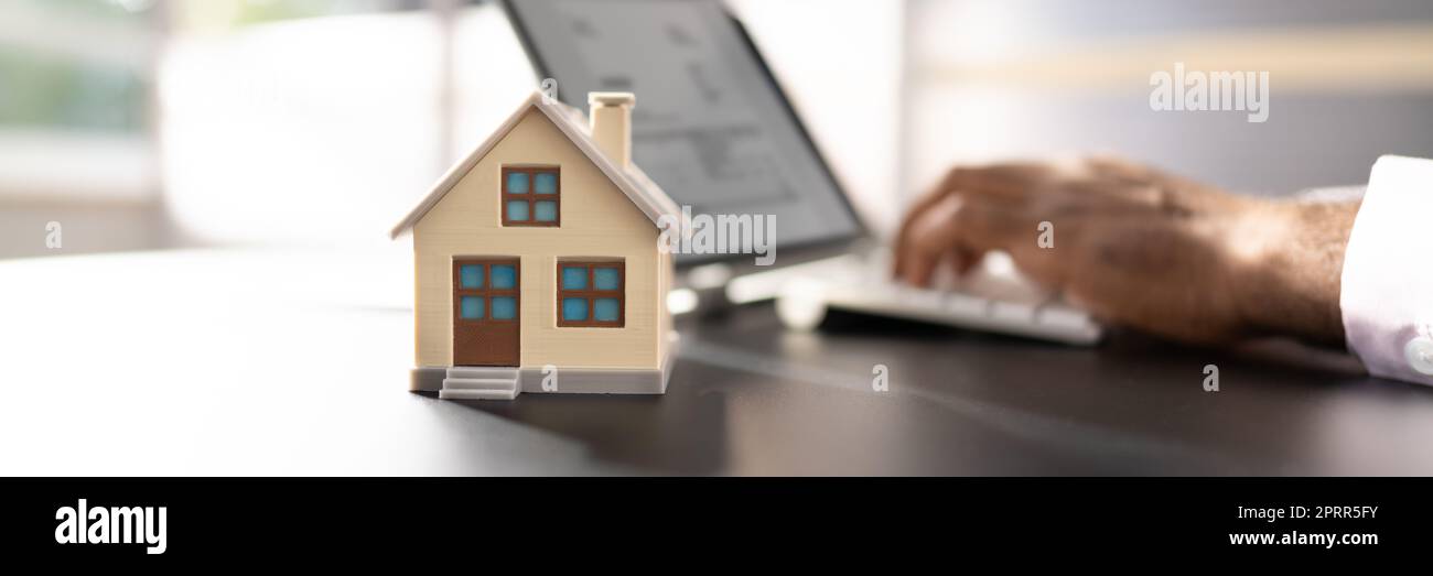 Modello Real Estate House vicino al computer portatile alla scrivania Foto Stock