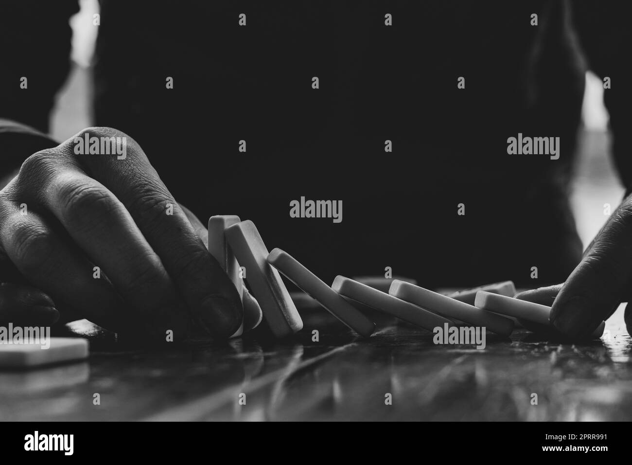 Mano femminile e domino su un tavolo di legno, foto in bianco e nero Foto Stock