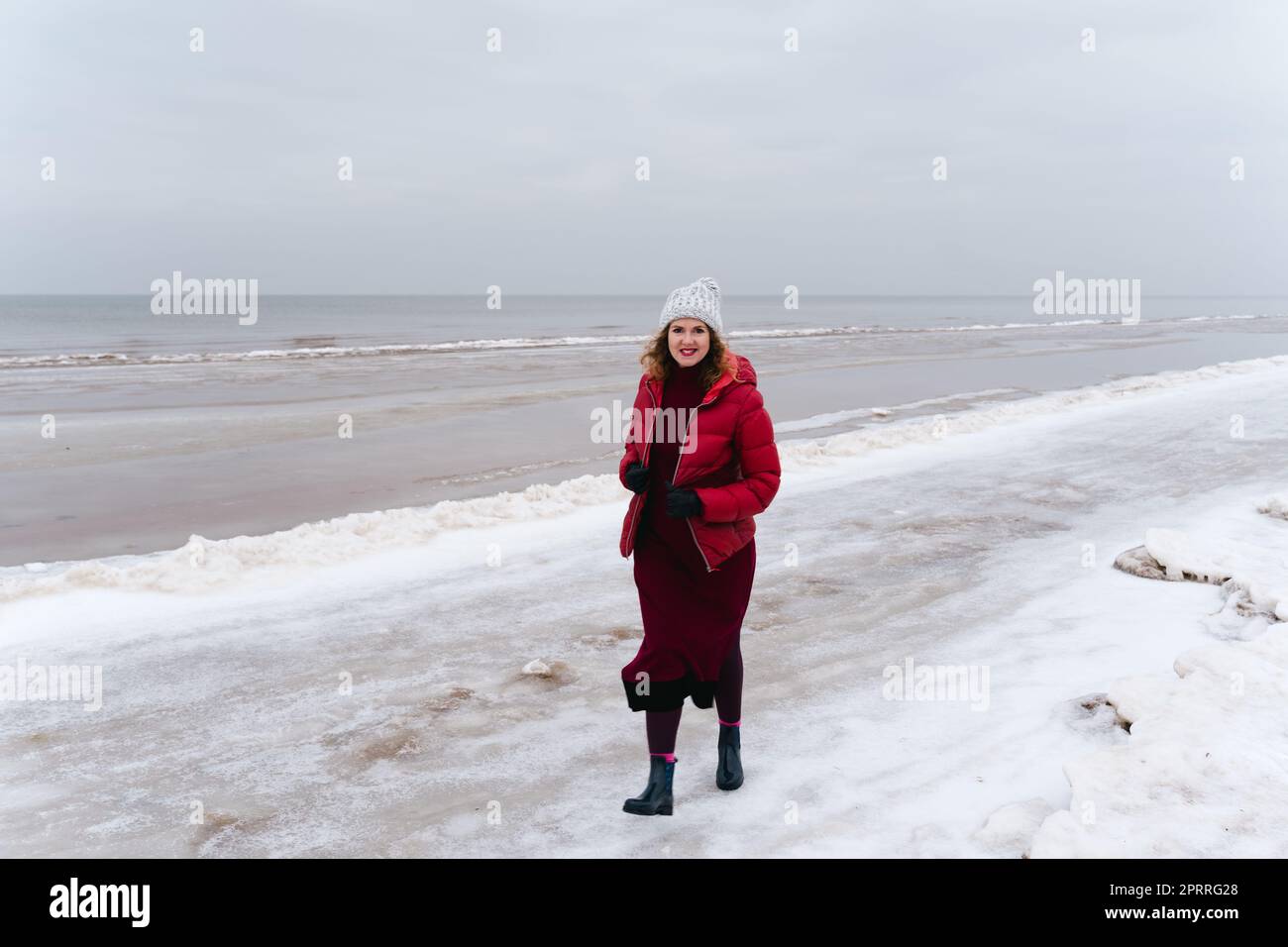Passeggiata invernale lungo il mare, una donna cammina e sorride Foto Stock