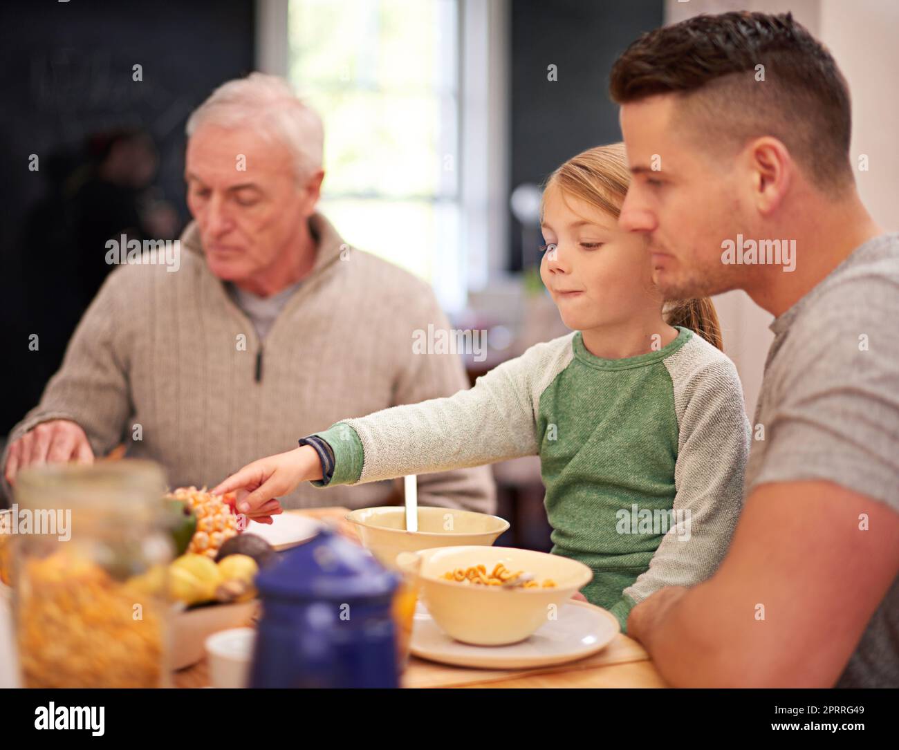 Adora la colazione: Una bambina che fa colazione con la sua famiglia in cucina. Foto Stock