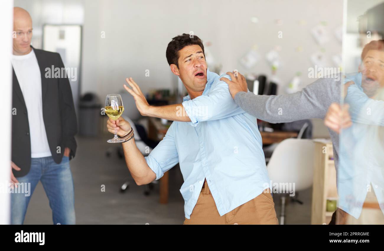 Il partito dell'ufficio è andato storto. Un uomo ubriaco che tiene un bicchiere di vino che entra in una lotta in un ufficio sociale. Foto Stock