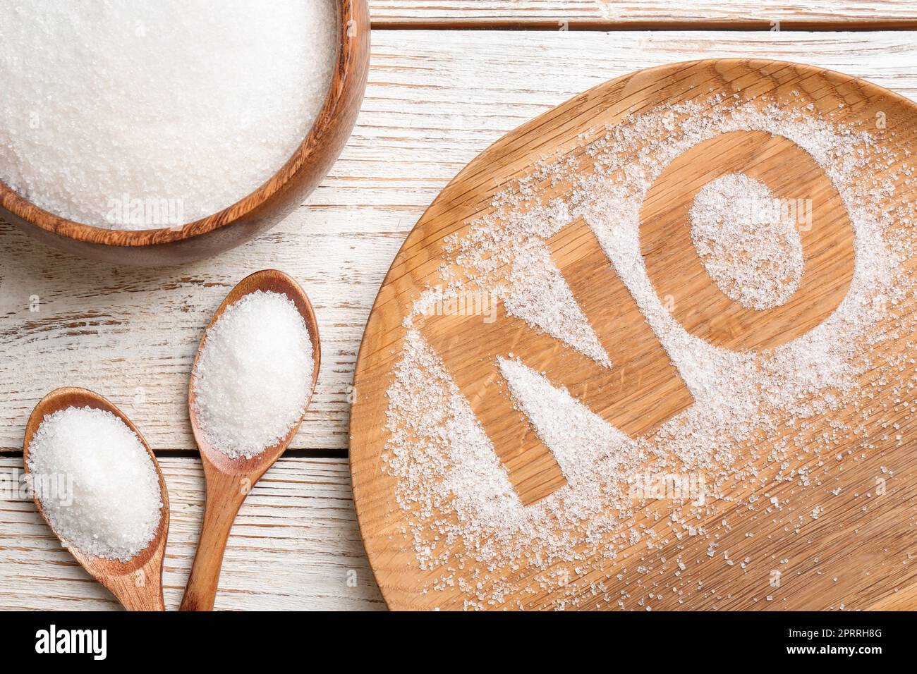 Niente zucchero. Composizione piana con granuli raffinati su tavola di legno bianco Foto Stock