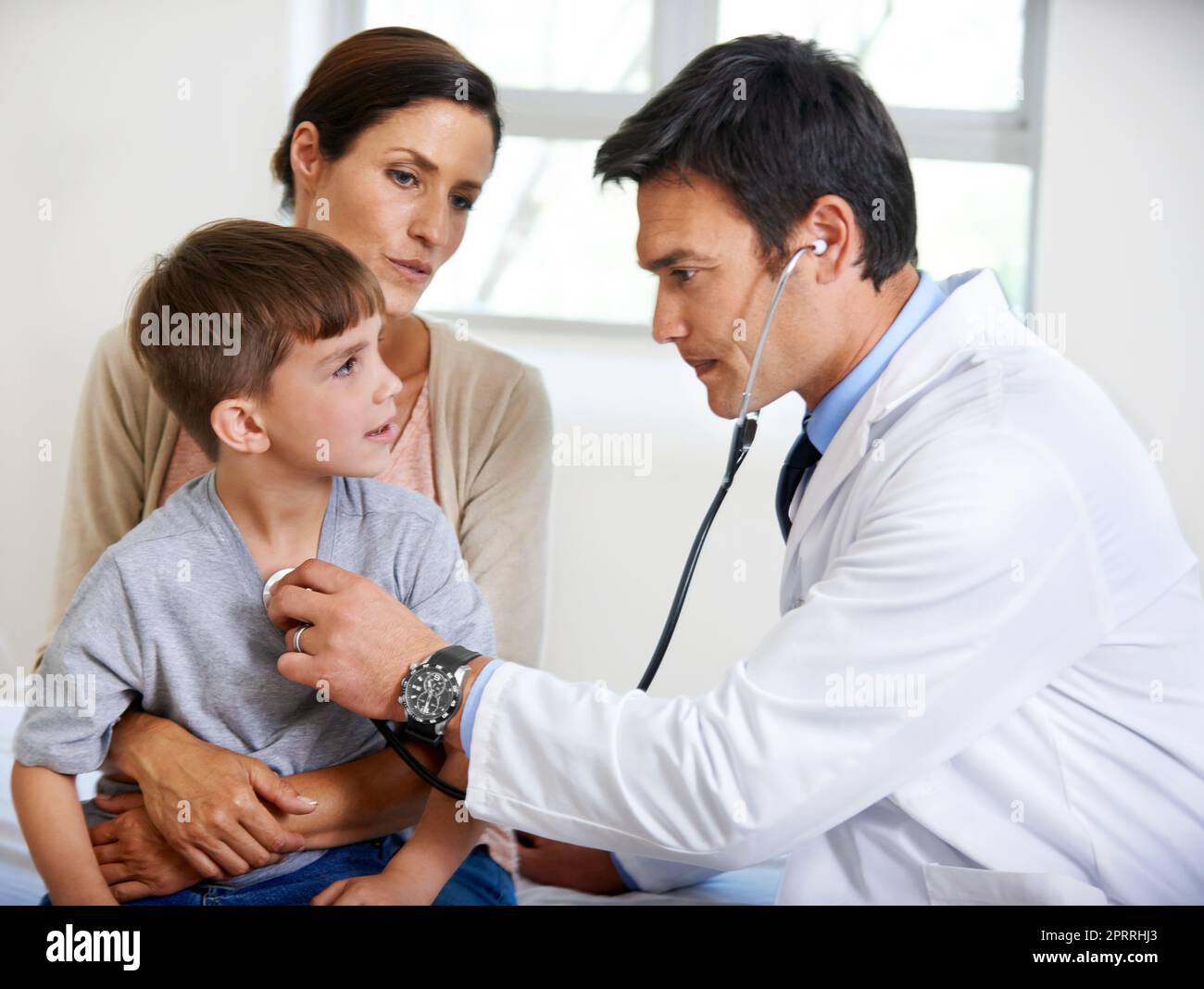 Questo ragazzino è pieno di vita, un medico interessato che esamina un giovane paziente. Foto Stock
