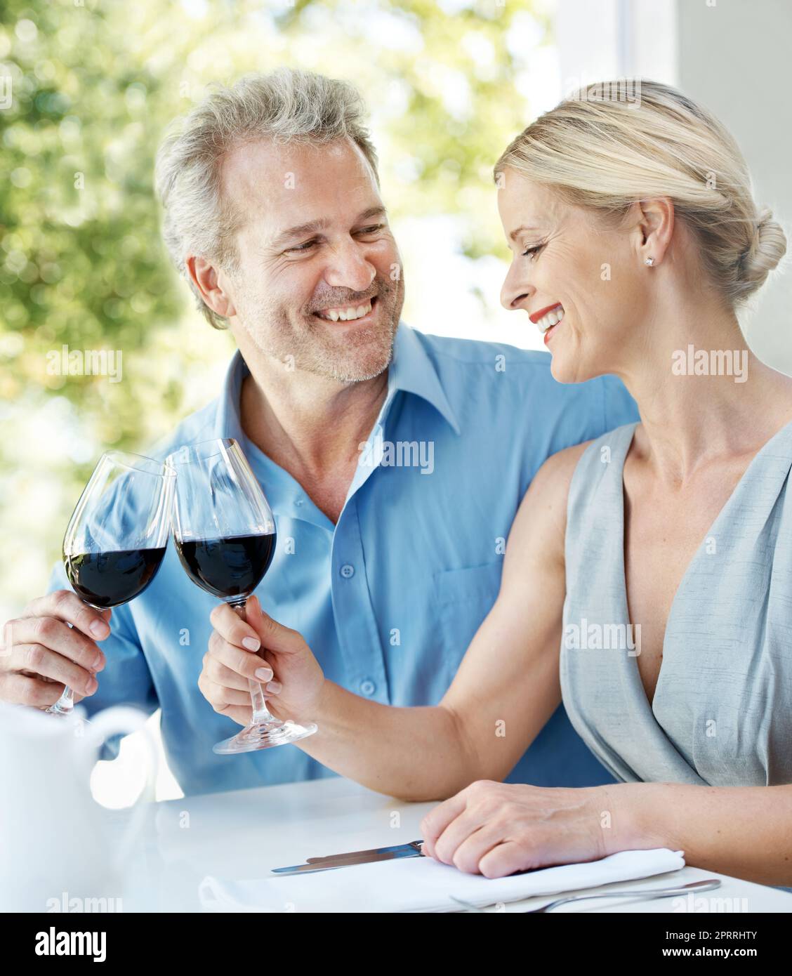 Heres a noi. Felice coppia matura brindando il loro amore con due bicchieri di vino mentre all'aperto. Foto Stock