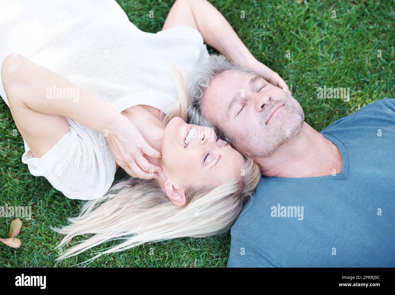 Questa è beatitudine. Una coppia matura sdraiata sull'erba sorridendo con gli occhi chiusi. Foto Stock