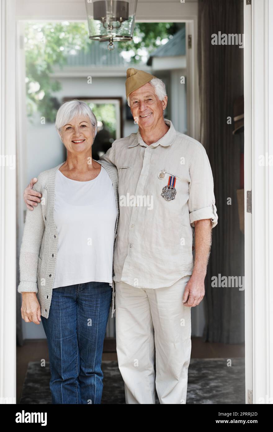 Patrioti orgogliosi. Un uomo anziano felice in piedi con la moglie che indossa la sua vecchia uniforme dell'esercito - ritratto. Foto Stock