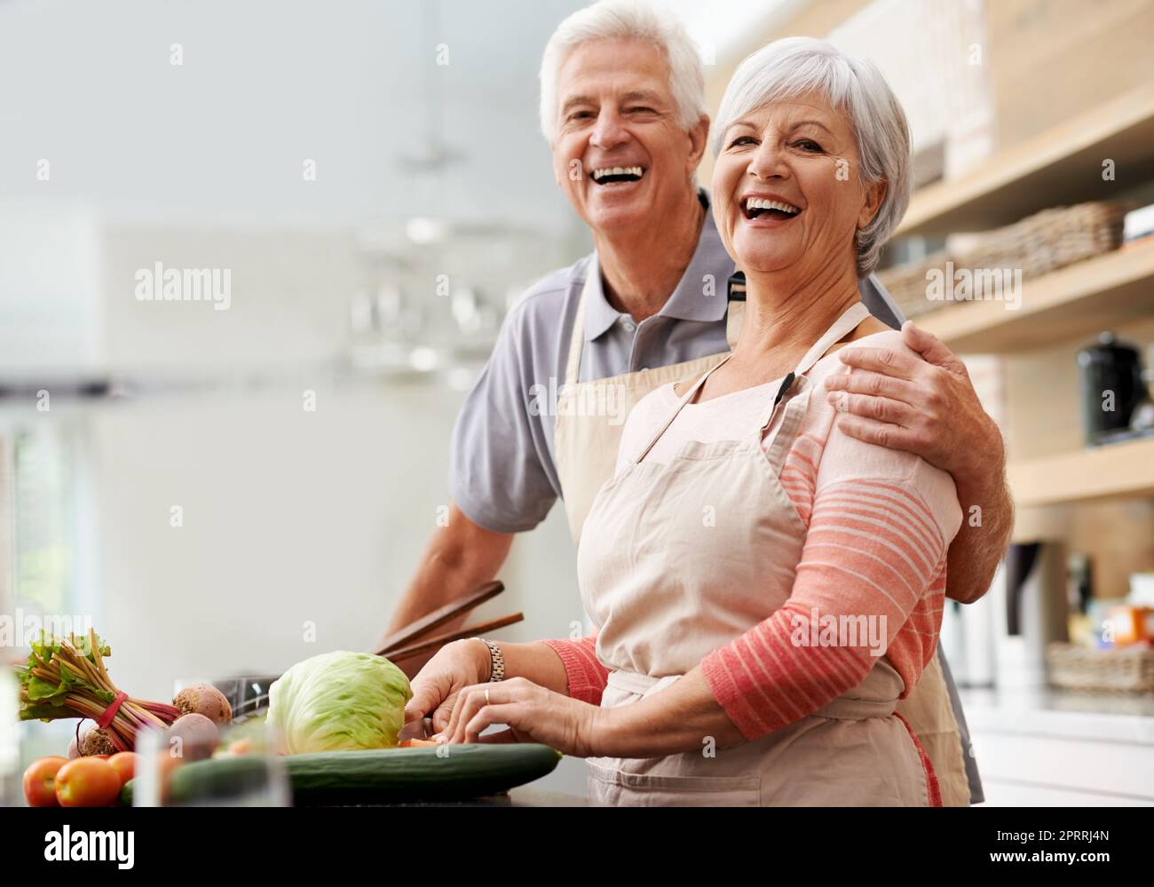 Tutto ciò di cui hai bisogno è amore... e senso dell'umorismo. Una coppia anziana ecstatica che ride in cucina. Foto Stock