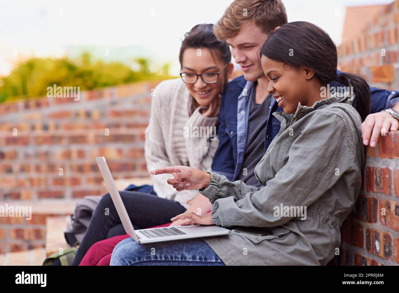 Imparare è piacevole. Un gruppo di studenti seduti fuori mentre si trovano nel campus. Foto Stock