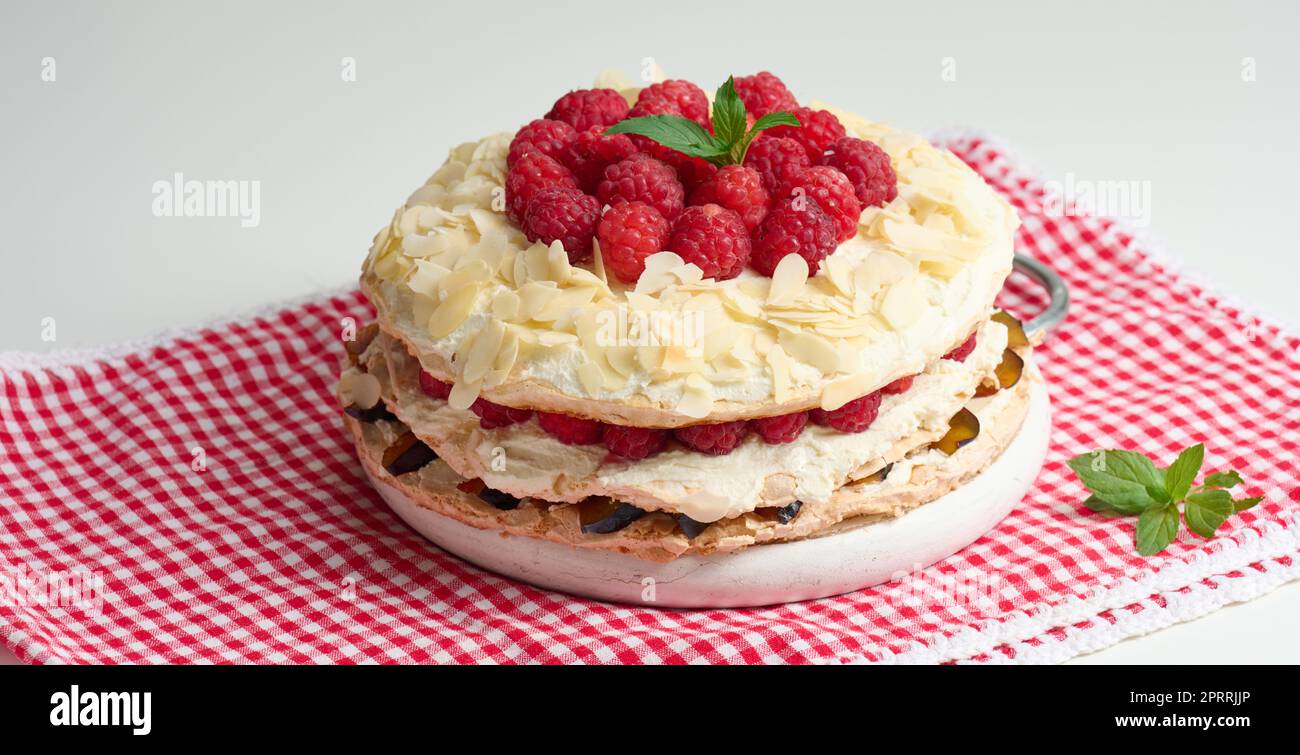 Torta di meringa rotonda con lamponi freschi su sfondo bianco, Pavlova dessert Foto Stock
