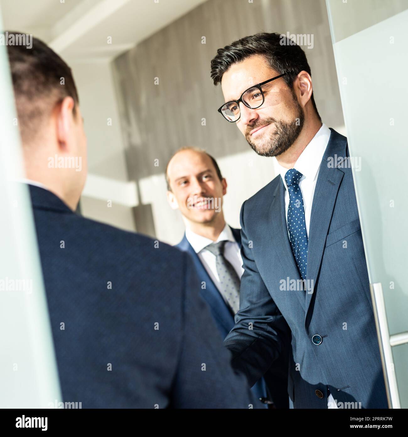 Gruppo di fiduciosi uomini d'affari salutano con una stretta di mano durante la riunione d'affari in ufficio moderno o chiudendo l'accordo di trattativa scuotendo le mani. Foto Stock