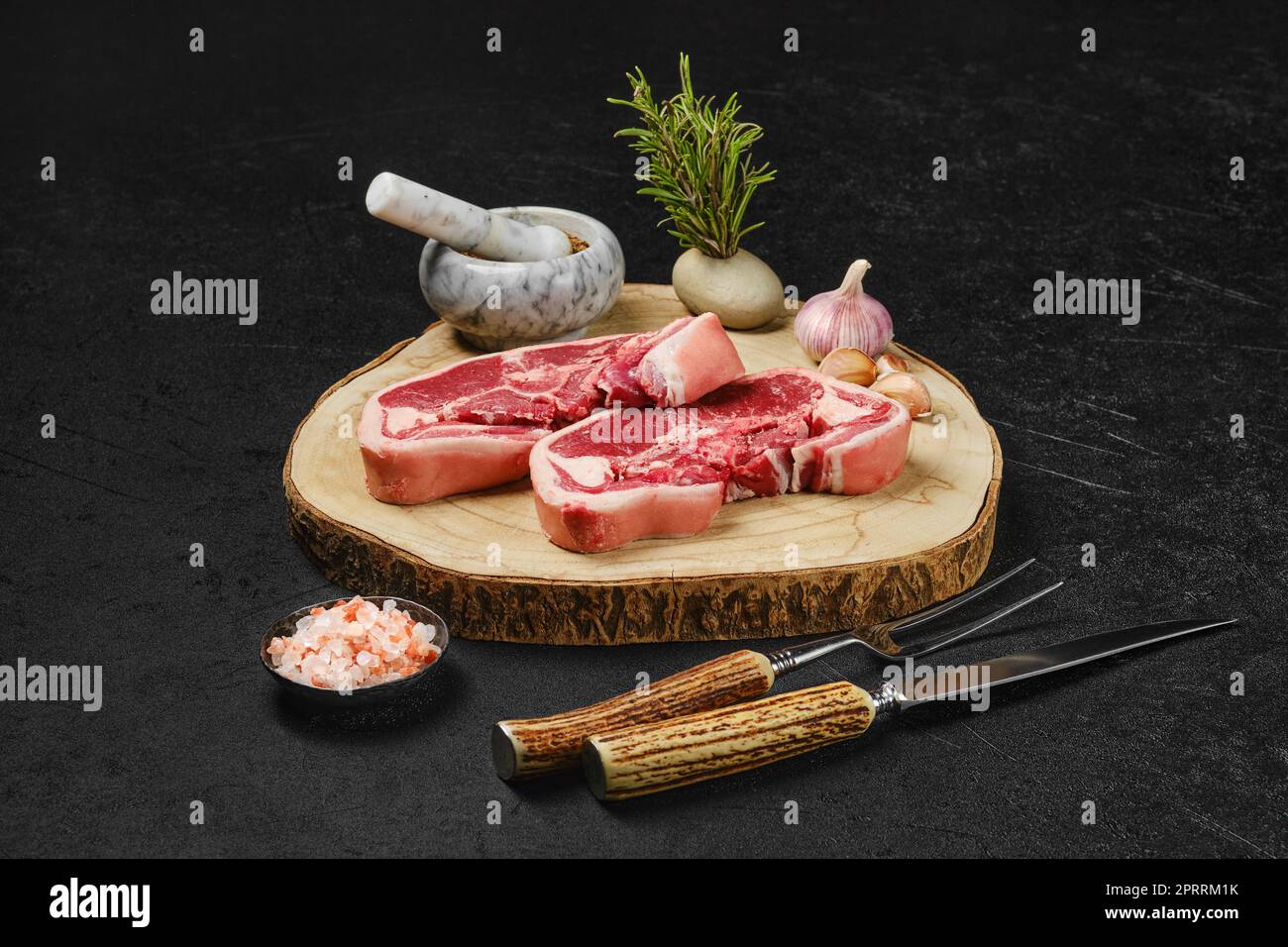 Tagliata a doppio filetto di agnello crudo con forchetta di carne, erbe e spezie Foto Stock