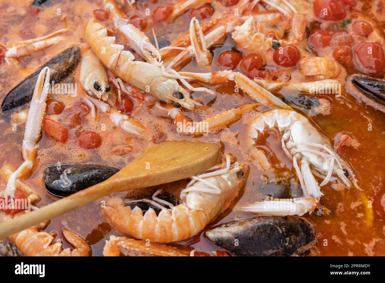 Cucinare spaghetti italiani allo scoglio, pasta con frutti di mare e pomodori da vicino in una padella Foto Stock