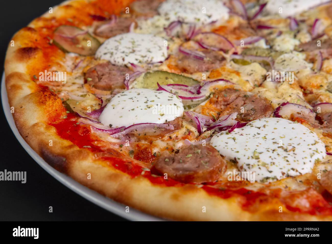 Primo piano della pizza con salsiccia, cetriolo sottaceto, la cipolla e il rafano. Messa a fuoco selettiva. Foto Stock