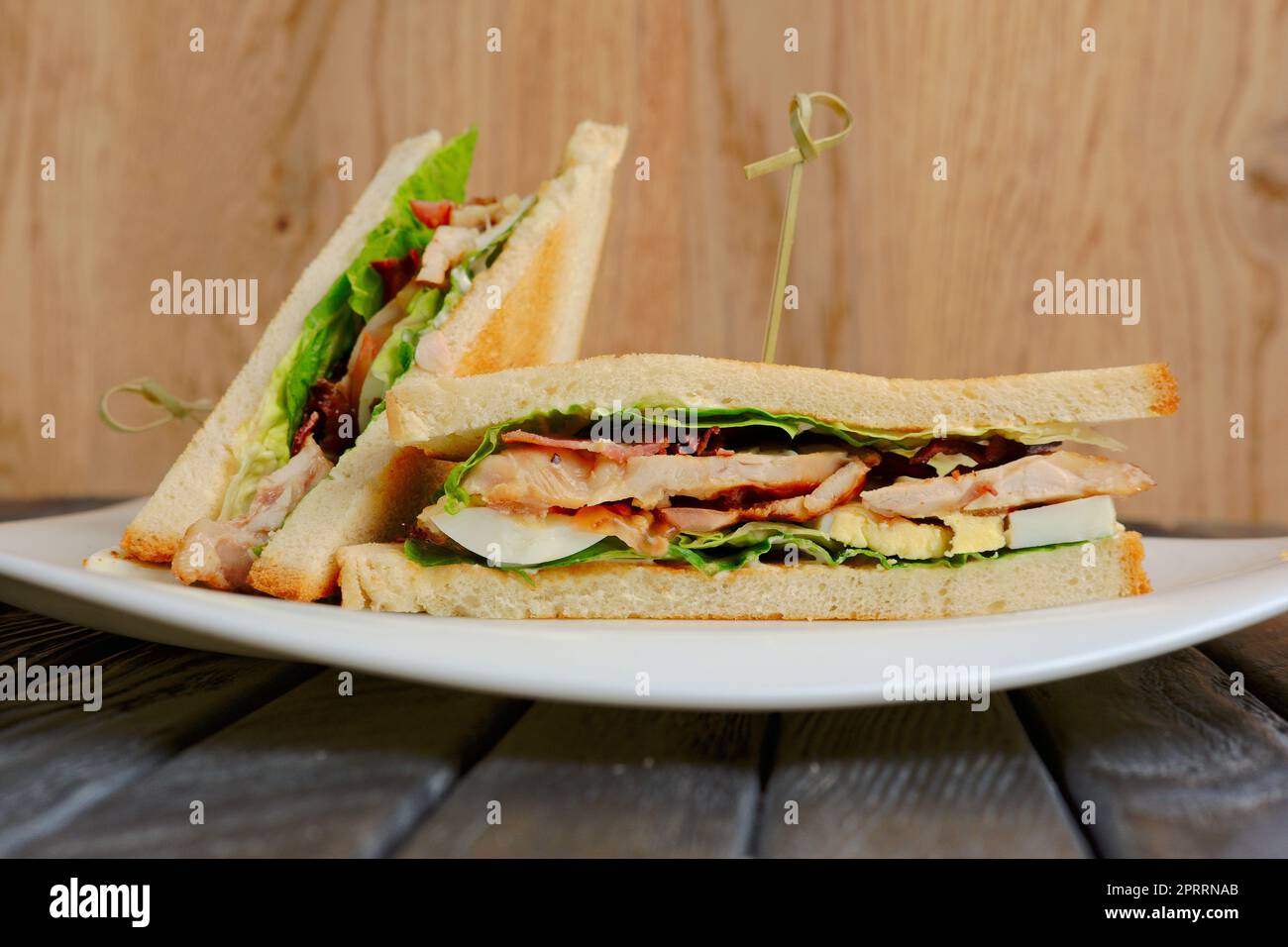 Piatto con panino club su tavolo di legno Foto Stock