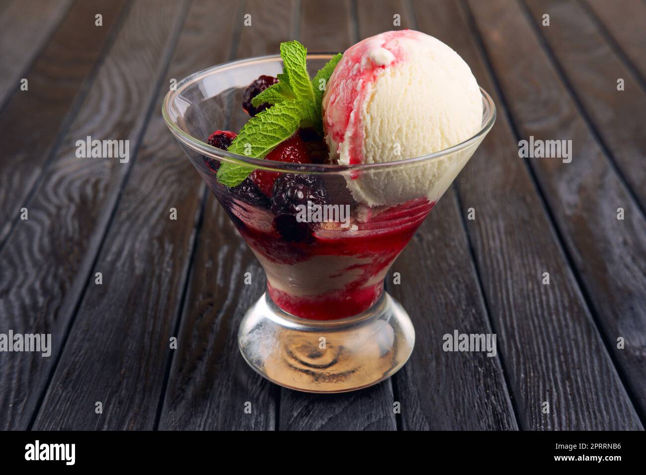 Una tazza di gelato ai lamponi decorato con foglie di mirtillo e menta Foto Stock