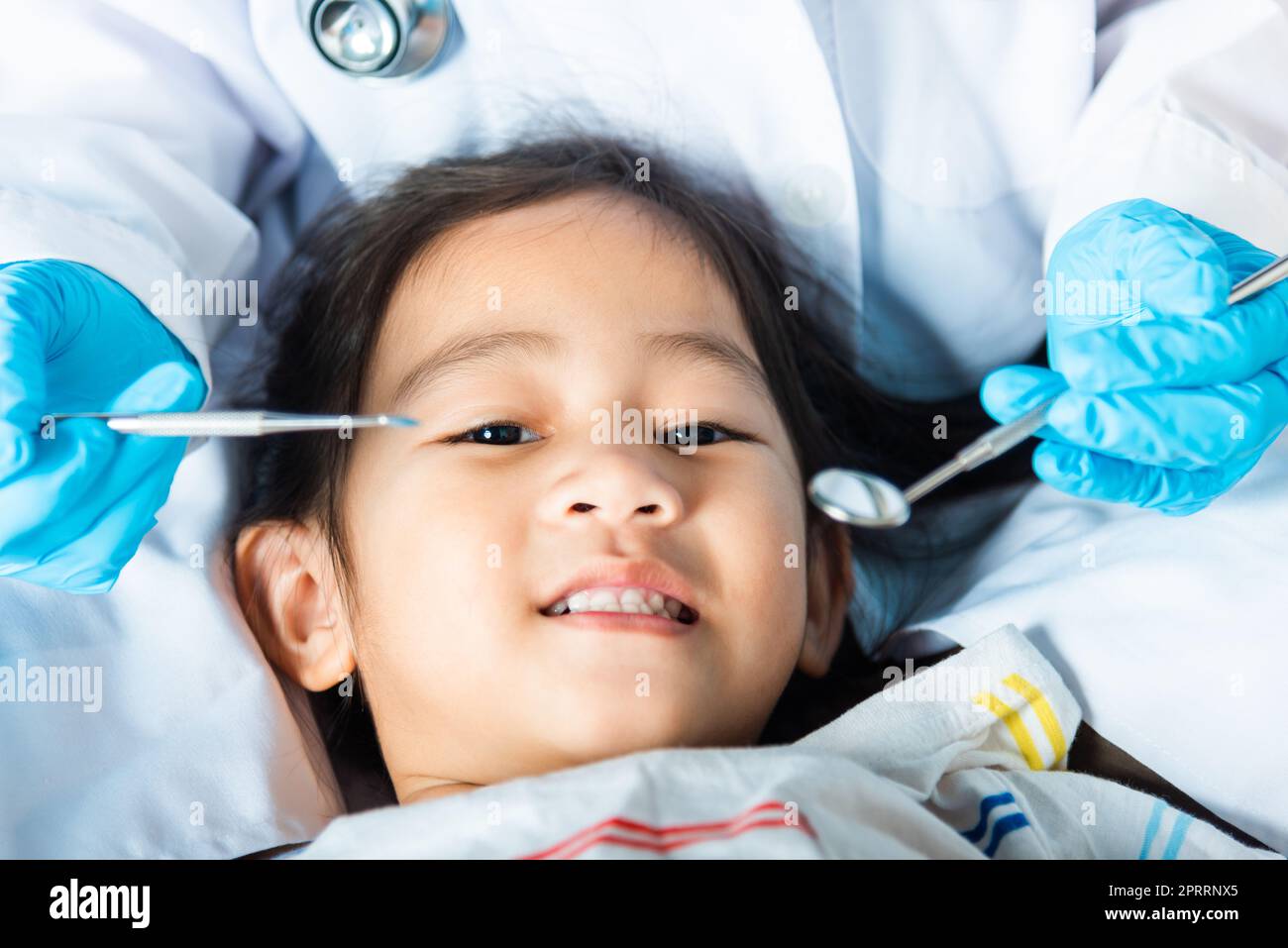 Il medico esamina la cavità orale del bambino piccolo usa lo specchio della bocca per controllare la cavità dei denti Foto Stock